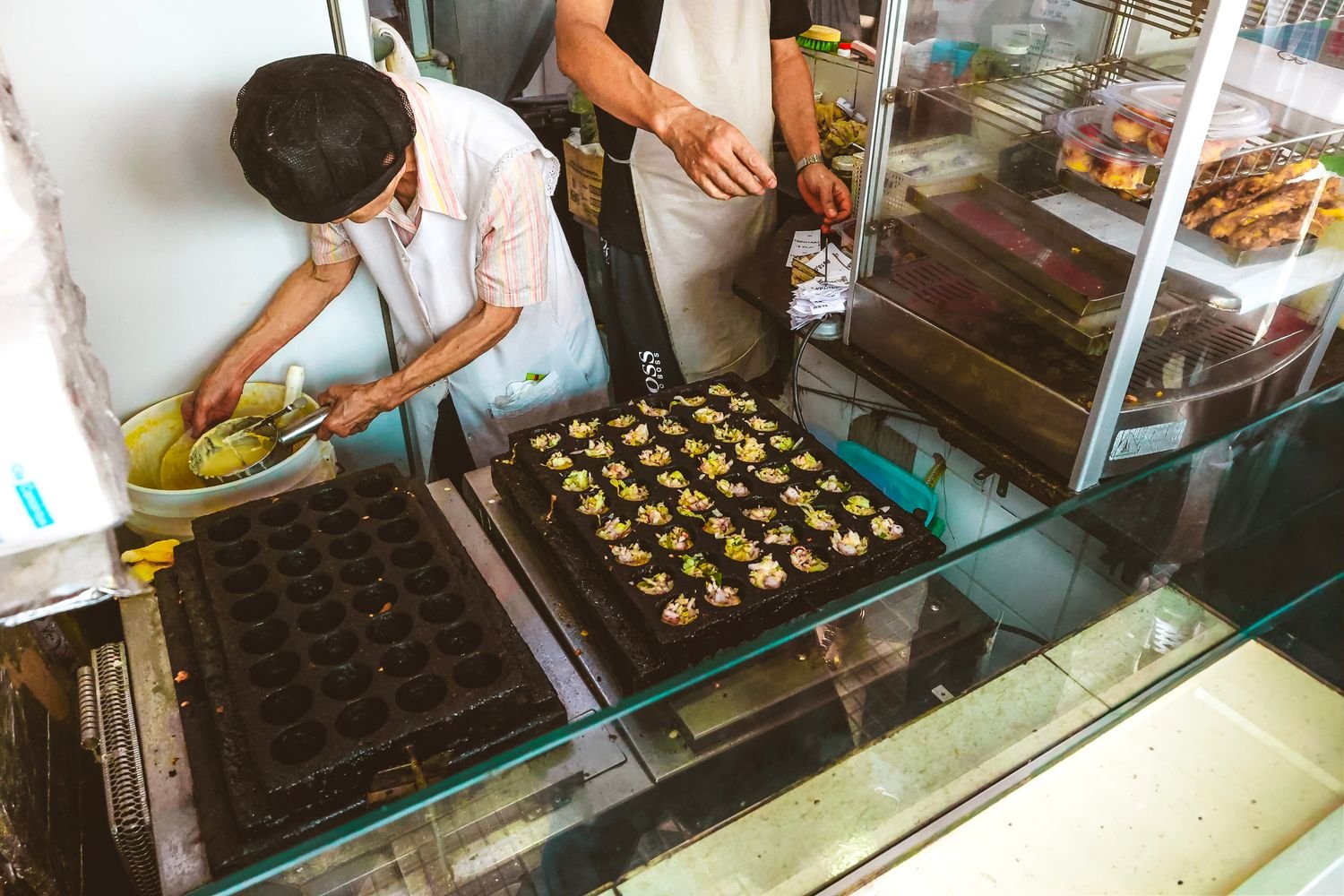 Street vendor preparing traditional takoyaki at a festival market stall