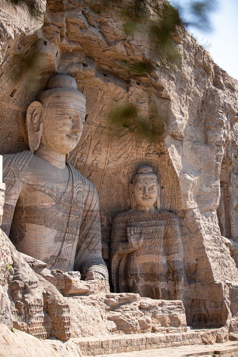 Large weathered stone bodhisattva statue carved into a rock cliff face