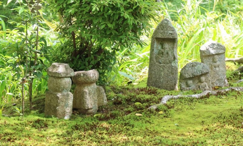 Moss-covered stone Jizo-style statues in a Japanese garden