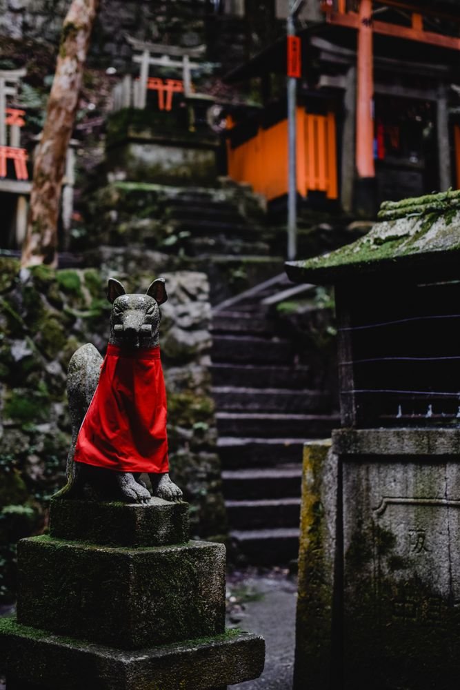 Stone fox statue with red bib at Fushimi Inari shrine in Kyoto
