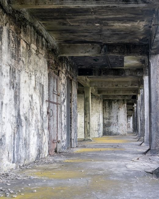 A weathered concrete corridor in an abandoned building, evocative of Gunkanjima's restricted walkways