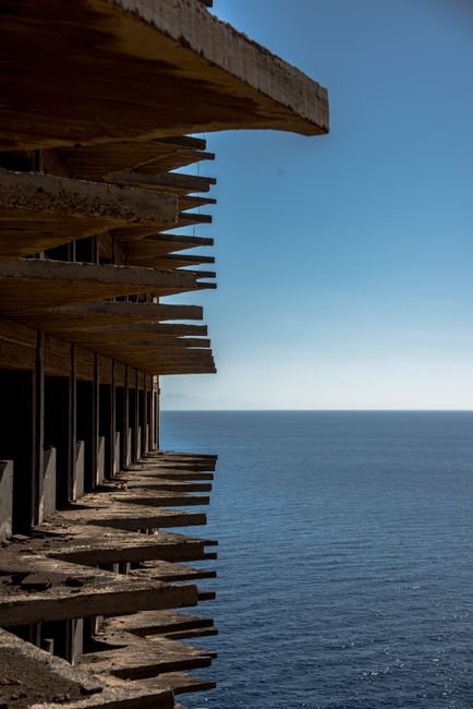 Weathered concrete building overlooking the sea, evocative of Gunkanjima / Hashima Island's ruins