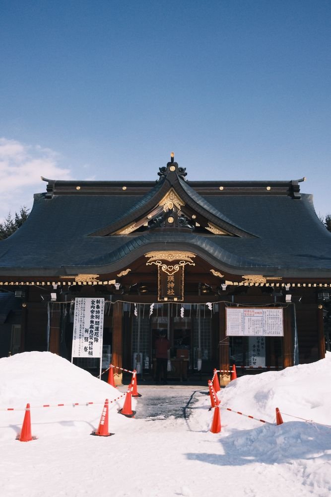 A snow-covered Japanese shrine building in rural Hokkaido during winter