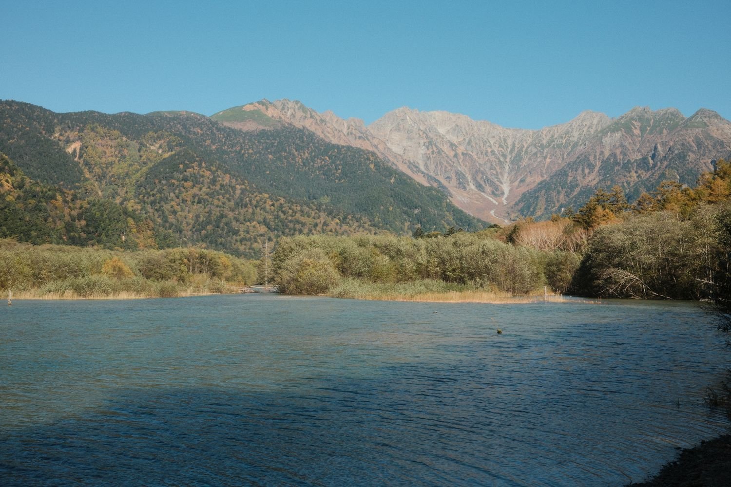 A peaceful pond with a mountain backdrop in Kamikochi National Park, Japan