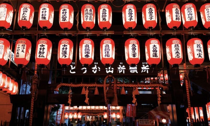 Rows of red paper lanterns lit at night during a Japanese festival