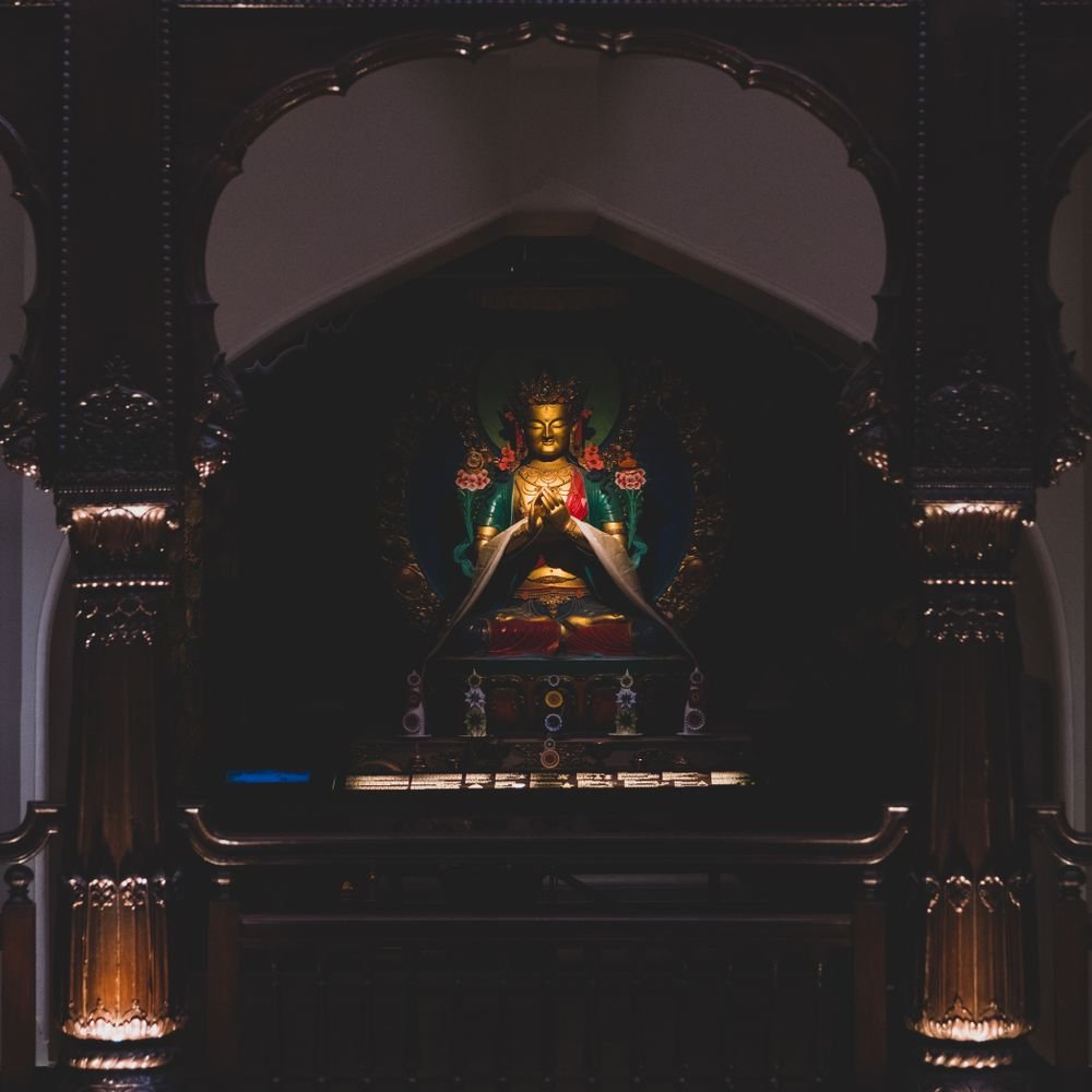 Golden Buddhist statue displayed within a richly decorated temple altar