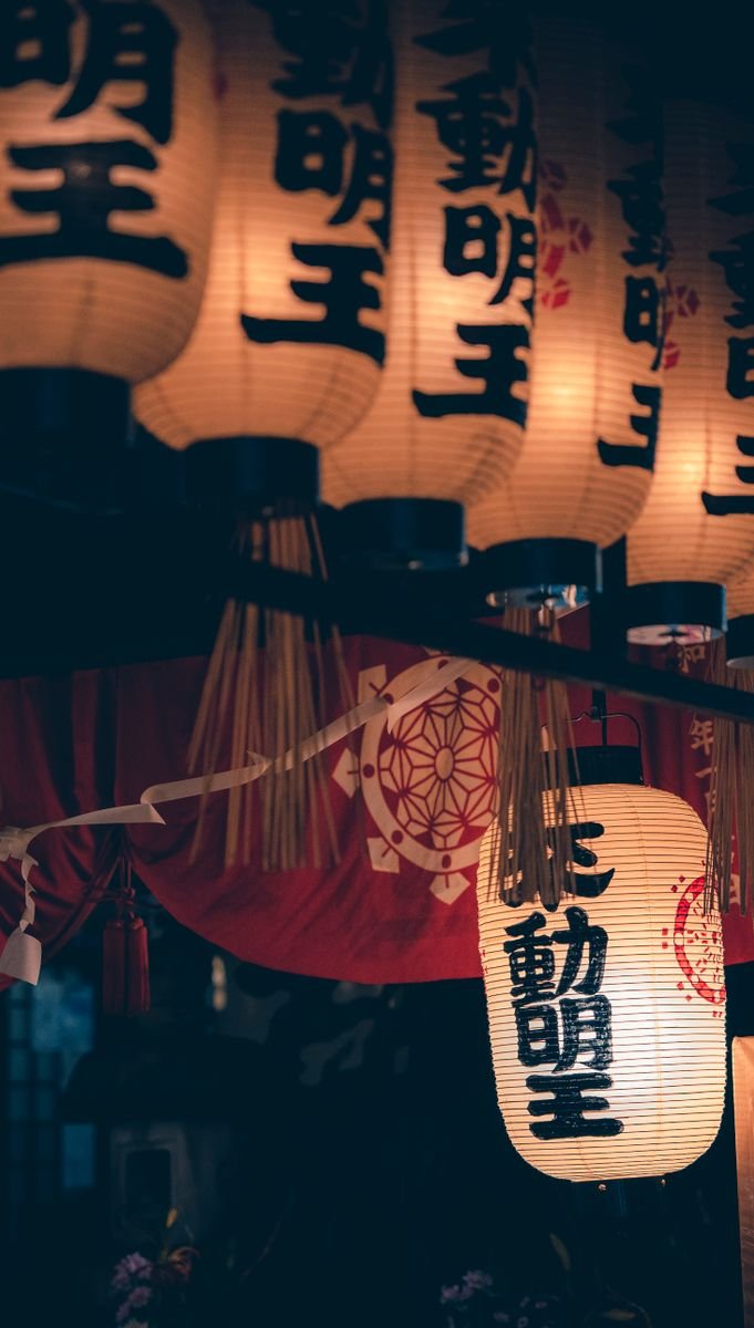 Traditional lanterns lit along a street at night, similar to the glow along Kurama's village lanes