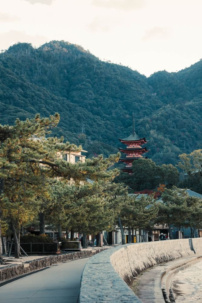 Serene landscape of a Japanese pagoda by forested mountains in Miyajima, Japan.