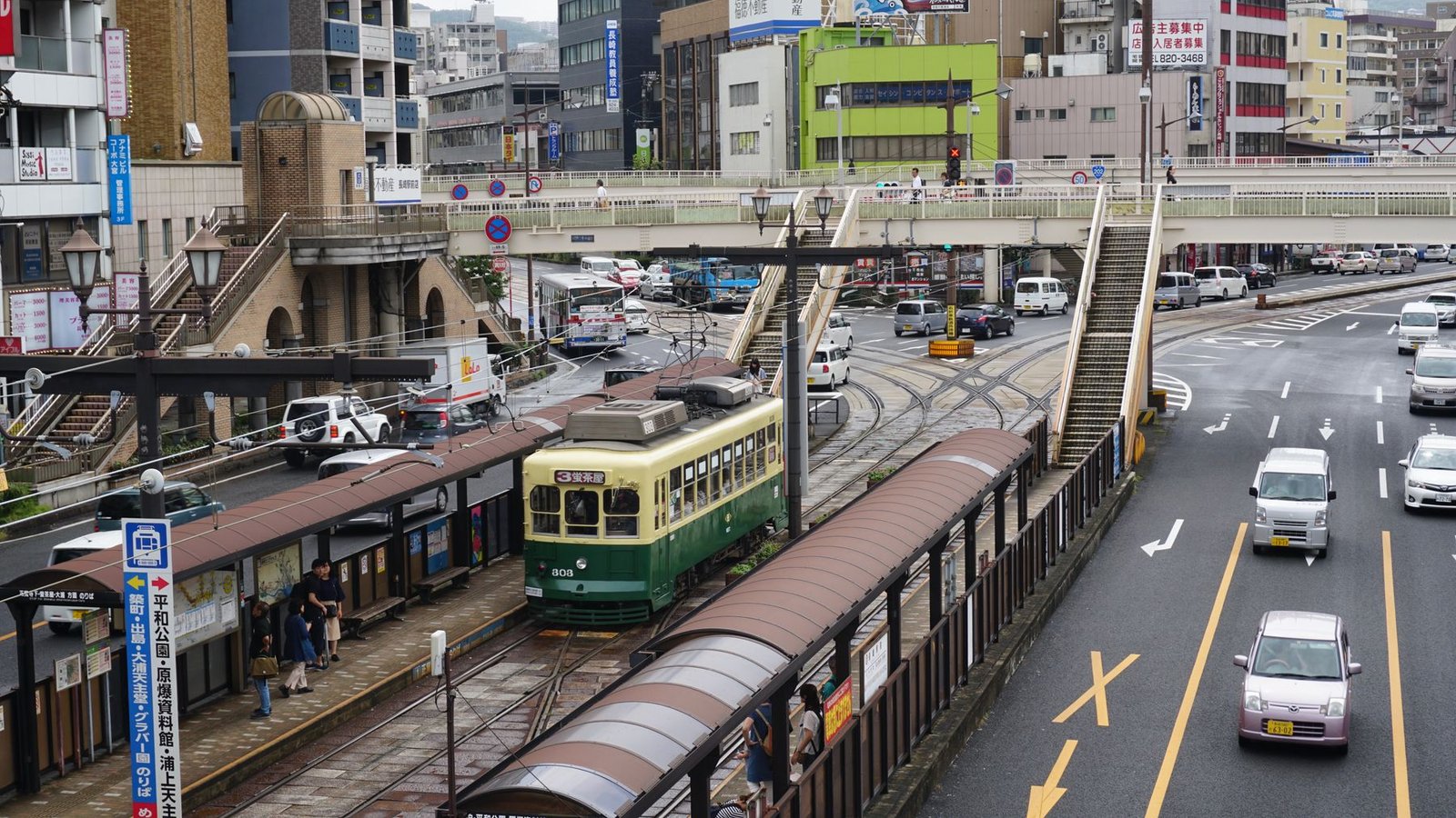A busy Nagasaki city street with tramway tracks and overhead lines