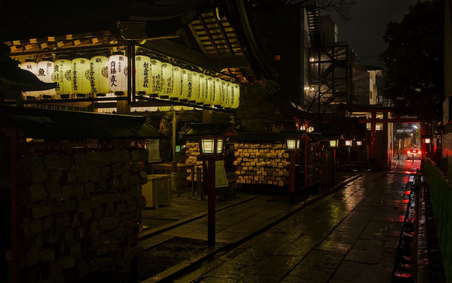 A quiet Japanese shrine street lit by lanterns at night
