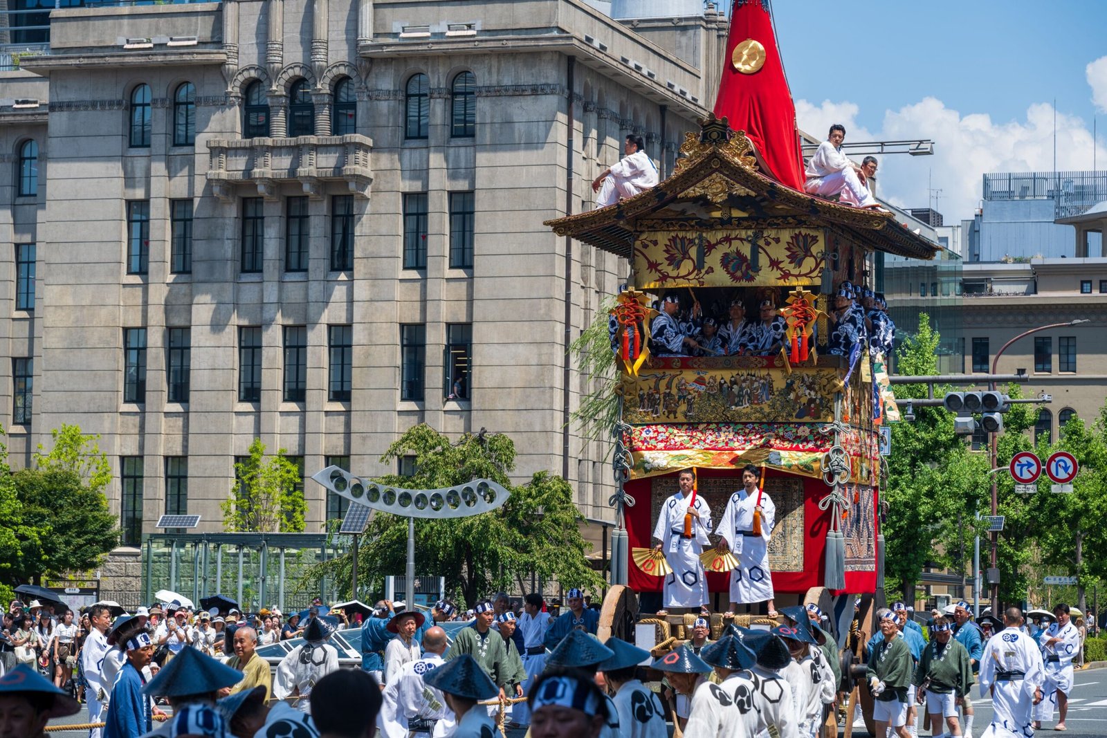 Traditional Japanese festival float with participants in traditional attire during a daytime parade