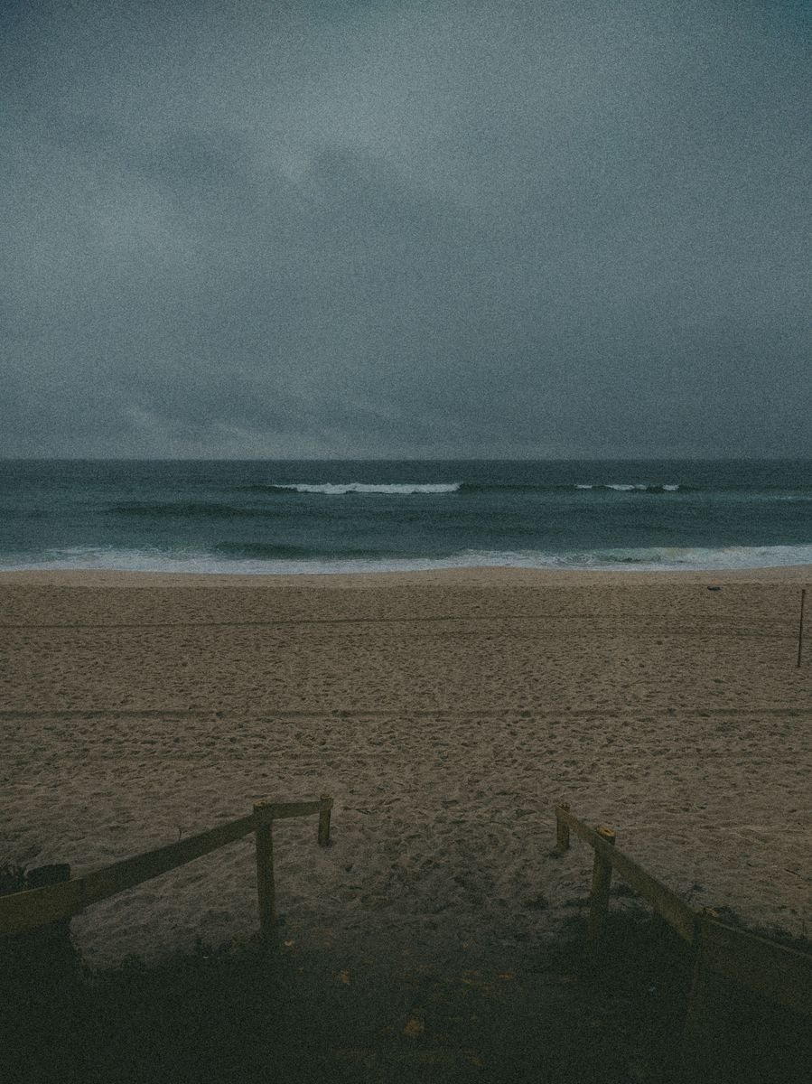 An empty overcast beach at dusk with gentle waves