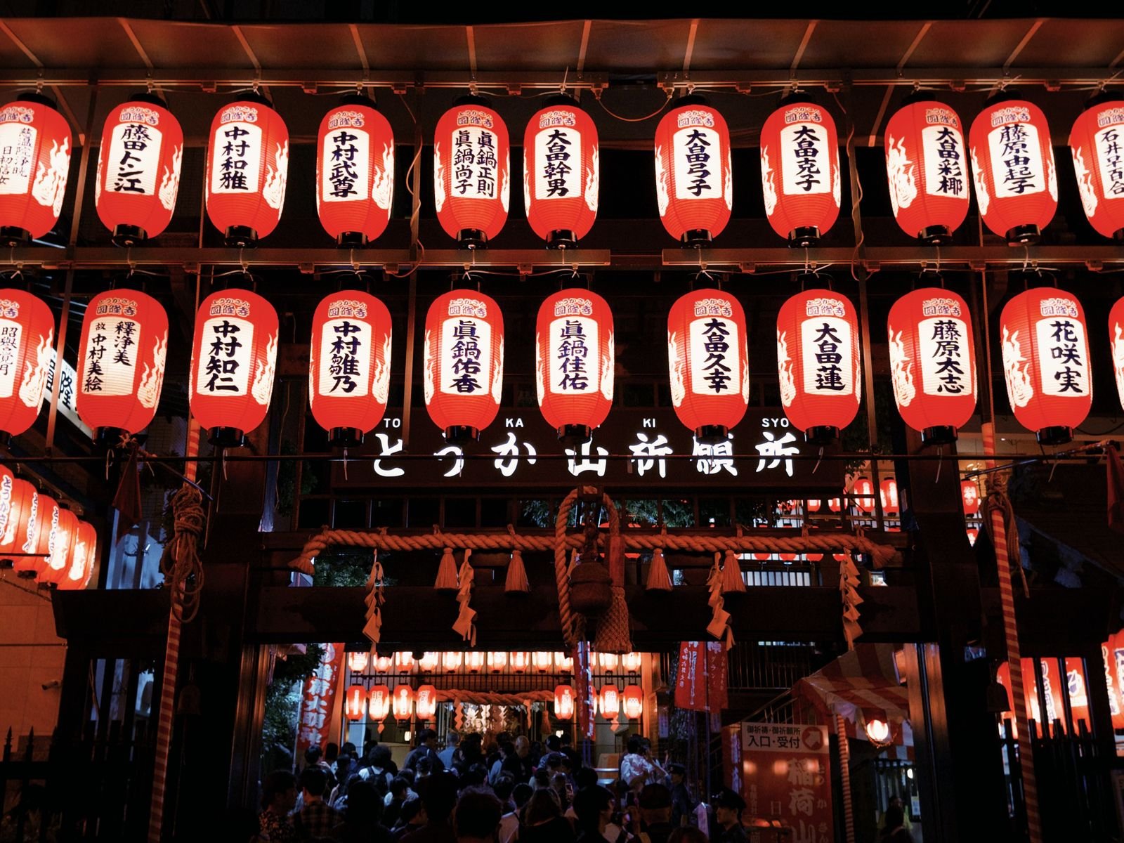 Glowing paper lanterns illuminating a crowded street festival at night in Japan