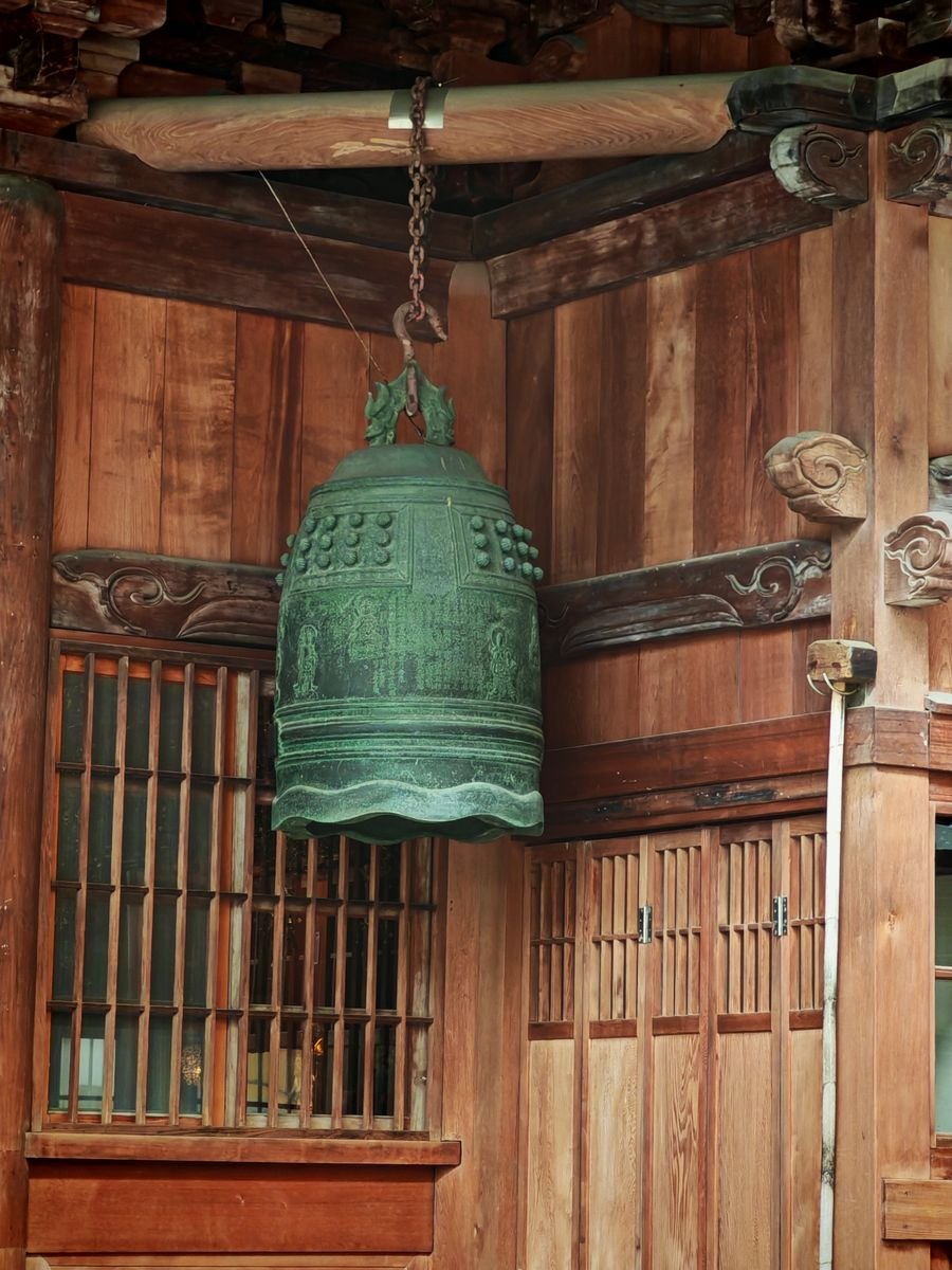 Ancient bronze bell hanging in a traditional Japanese wooden structure