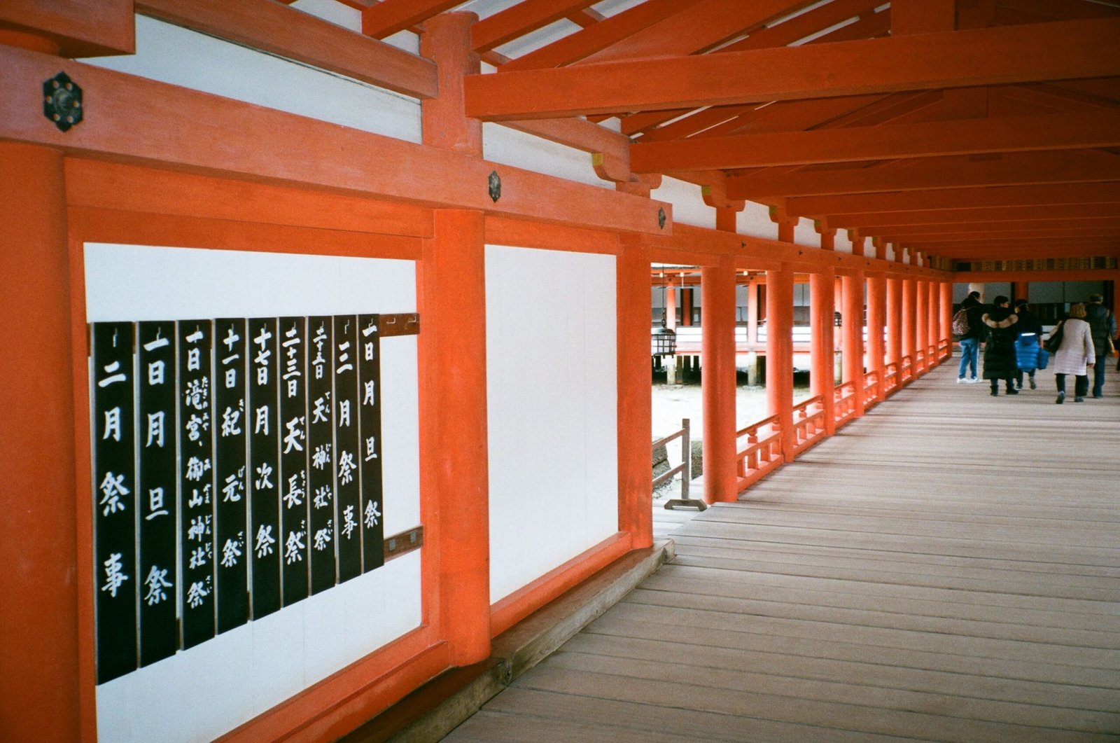 Wooden temple corridor with visitors walking through