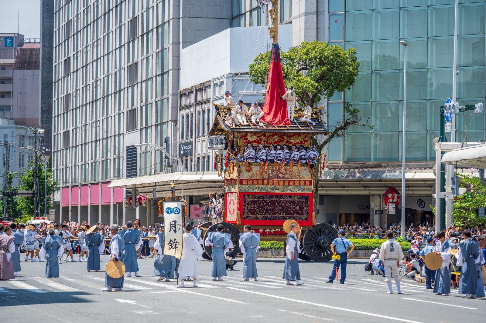 Traditional Japanese festival float being pulled through the street by a crowd in matching coats