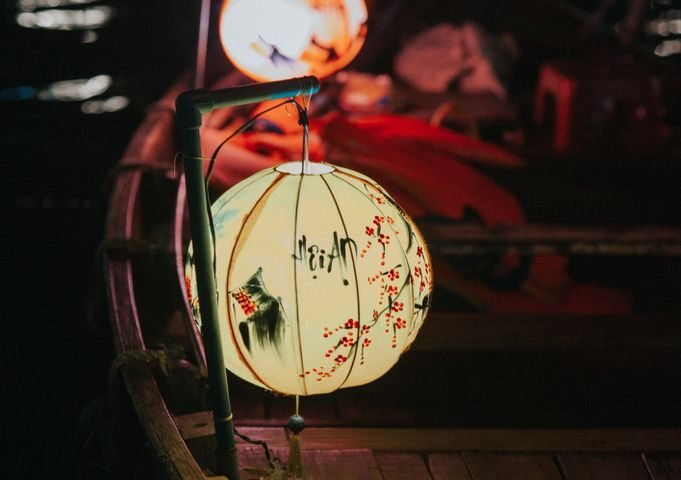 A traditional lantern-lit wooden boat on the water at night