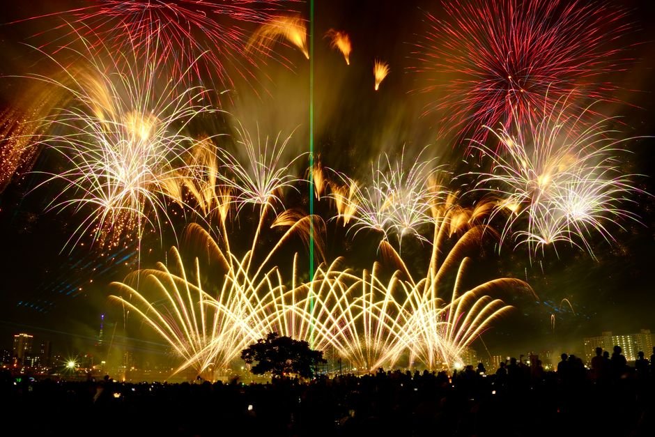 Fireworks exploding in the night sky above a crowd at a Japanese festival