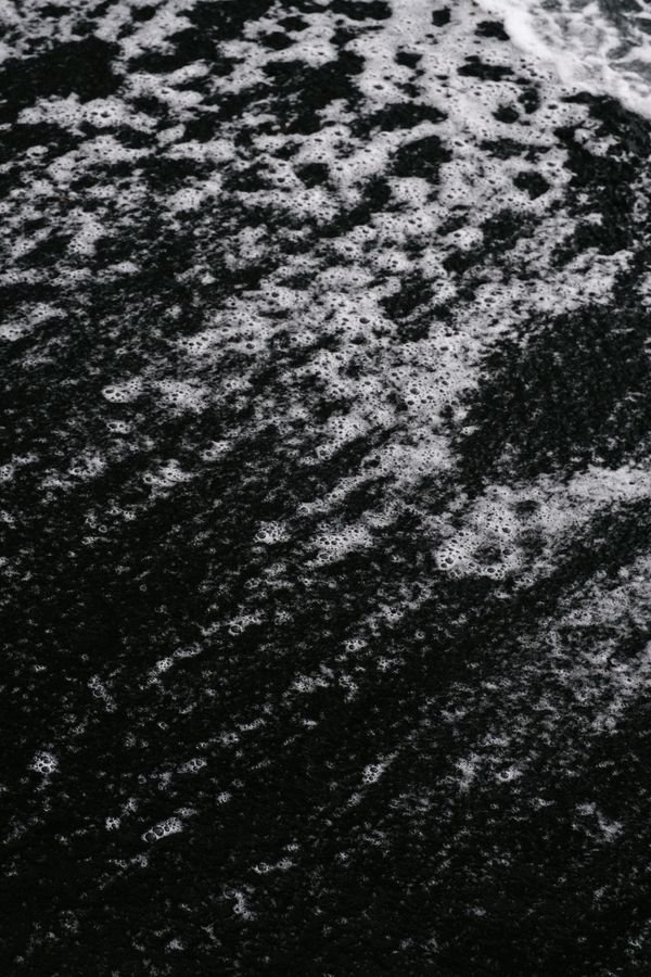 Dark volcanic sand beach with wave patterns