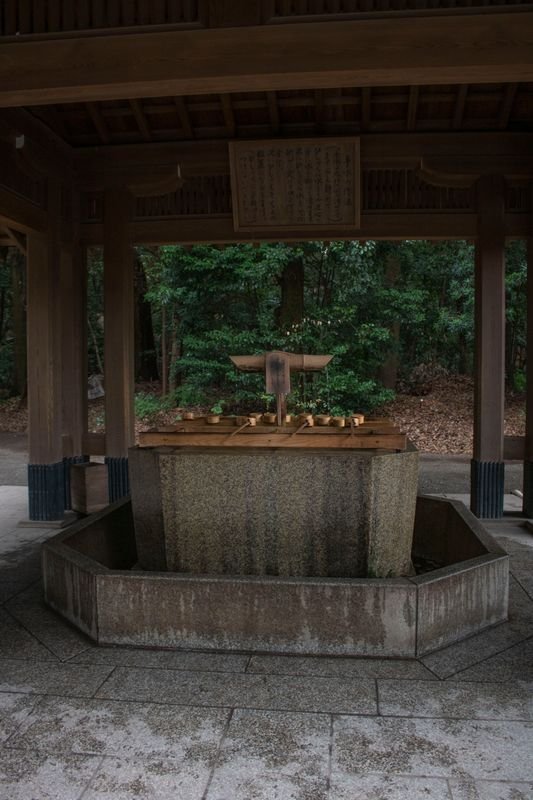 A traditional stone well at a Japanese shrine, surrounded by greenery