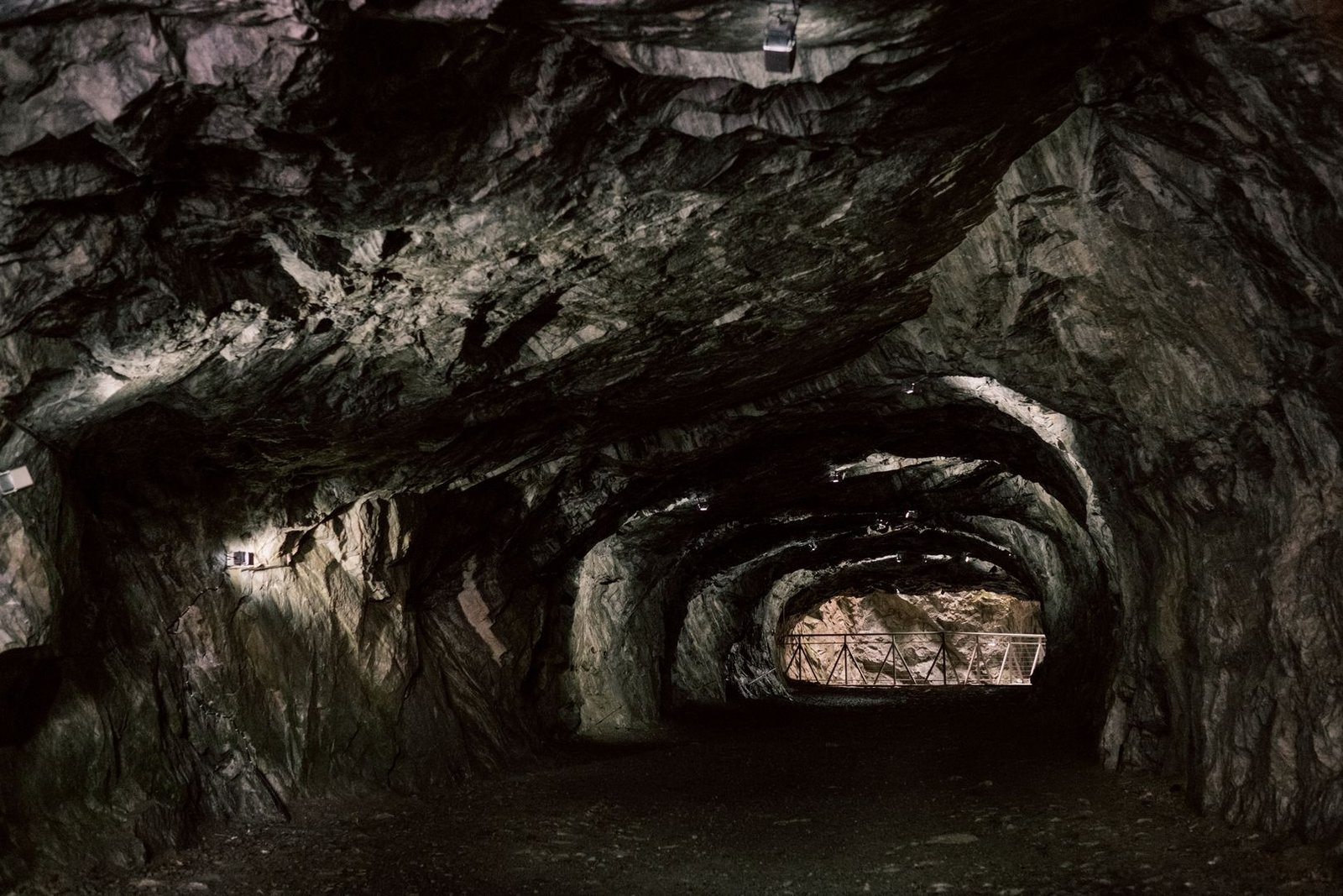 A dim footpath disappearing into a dark cave