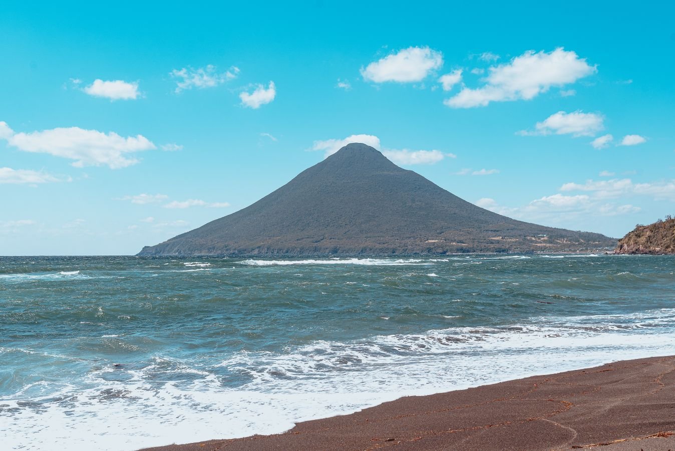 Volcanic mountain rising above a beach and ocean