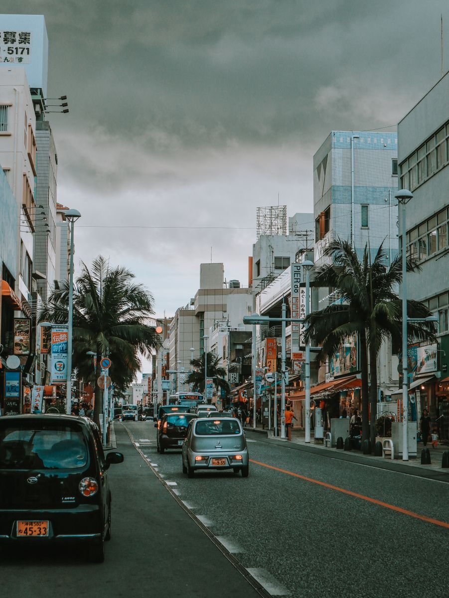 A busy street in Naha, Okinawa, lined with palm trees at dusk