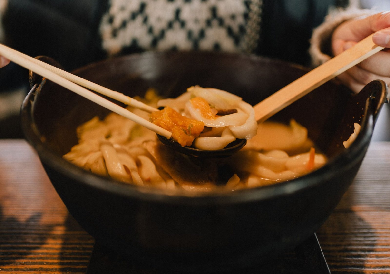 Japanese udon noodle soup in a dark bowl with chopsticks