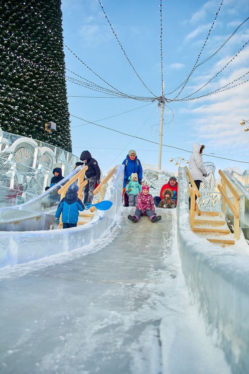 Children sliding down a snow slide at a winter festival