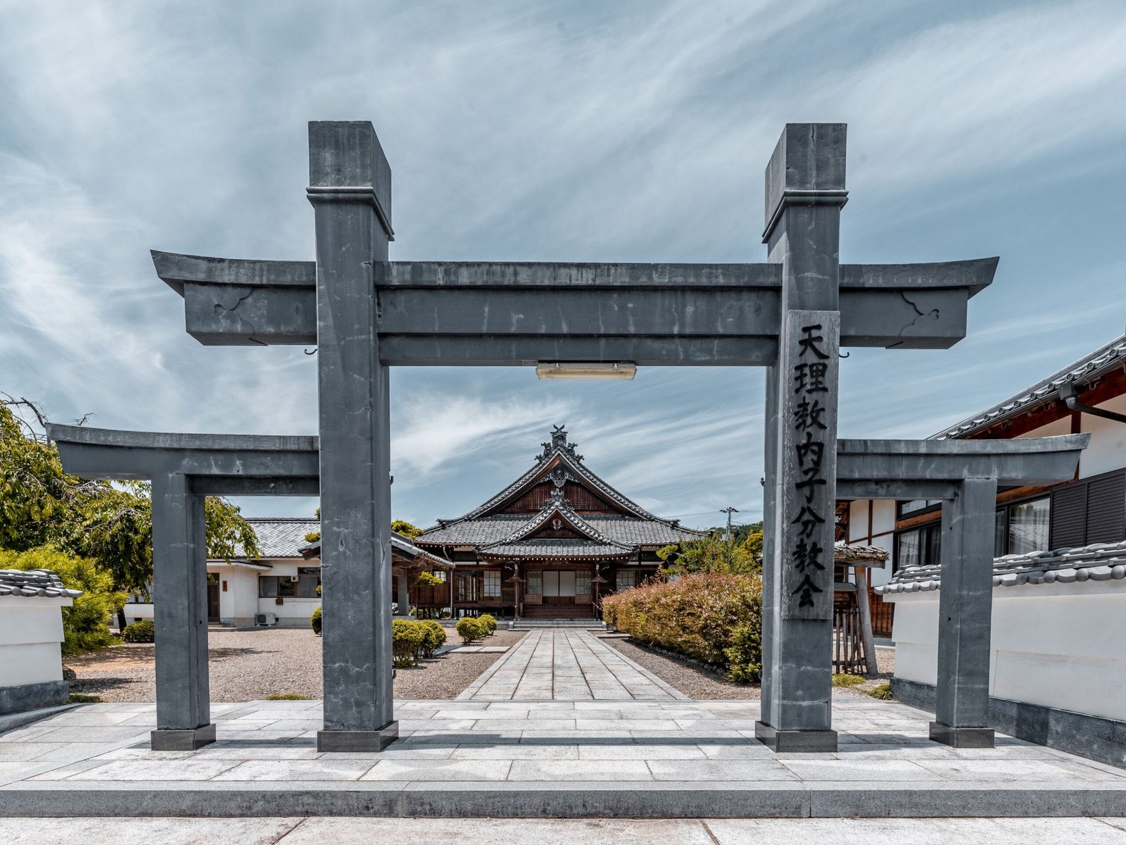 Stone steps leading up to a Japanese temple gate surrounded by forest